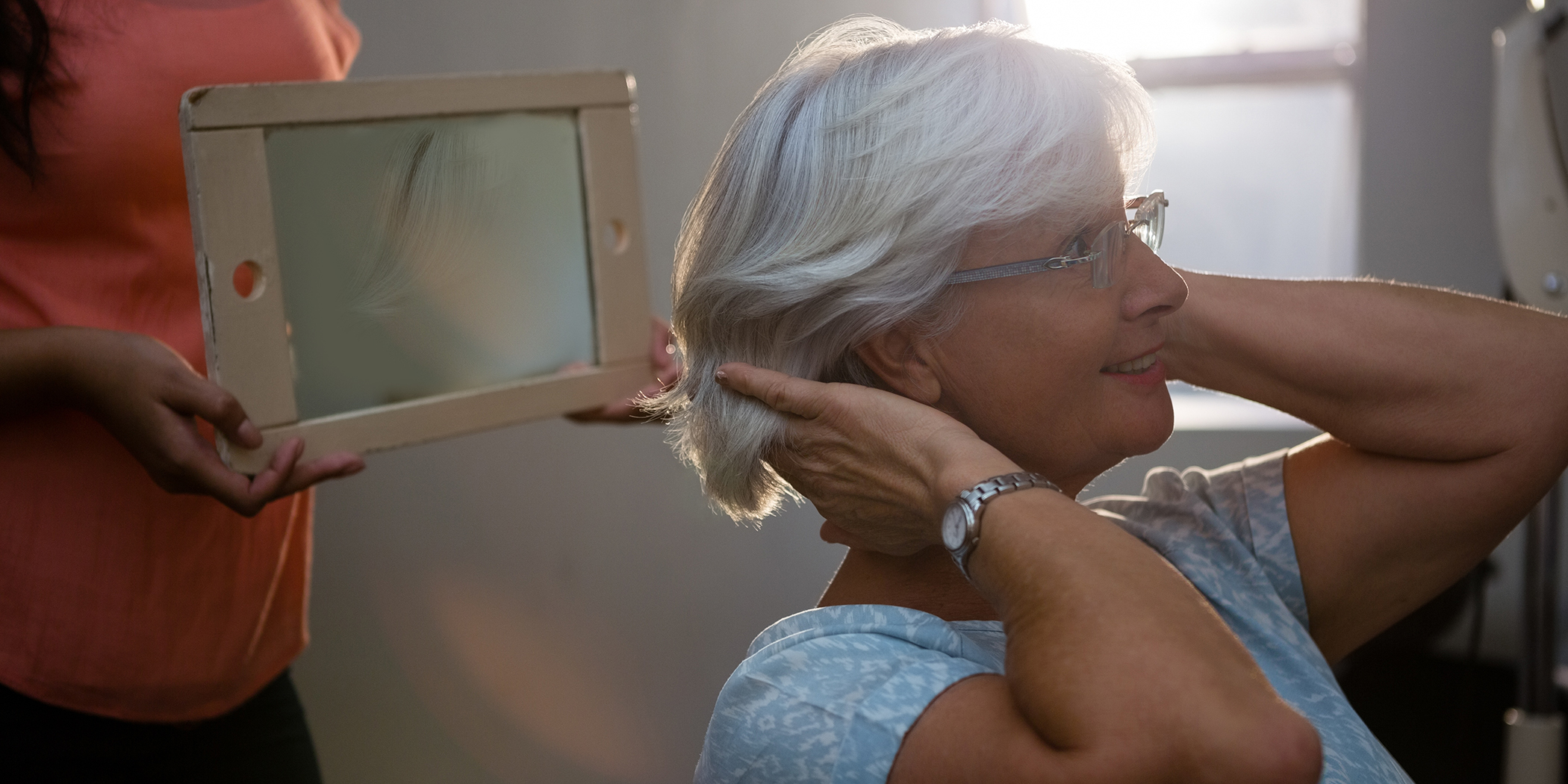Senior woman looking at her new haircut in the mirror